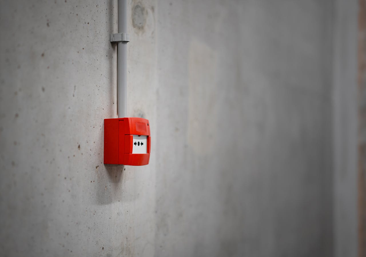 our-story A red alarm box mounted on a gray concrete wall, offering urban security.