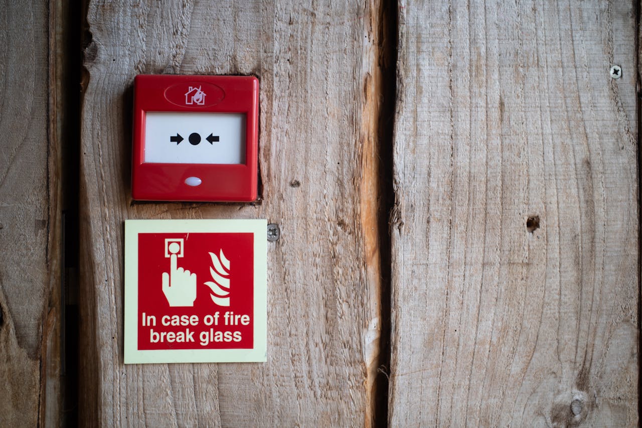 home-img Red fire alarm and warning sign on a rustic wooden wall for safety awareness indoors.